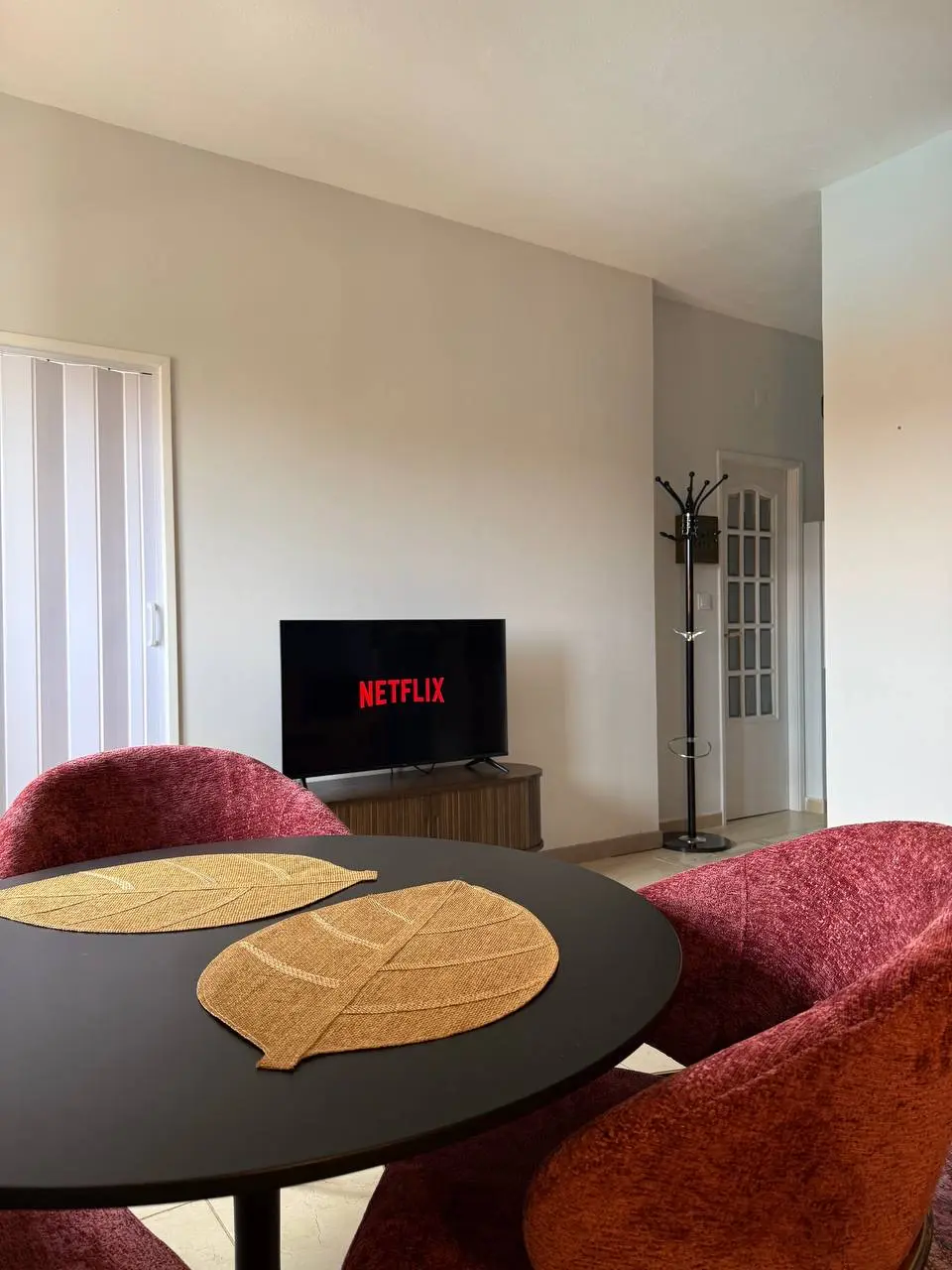 Round dining table with four rose chairs facing the TV in the living room
