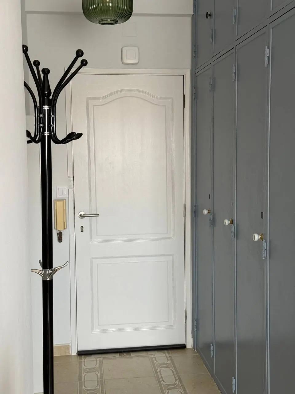 Entry corridor with front door, coat stand, and tall built-in storage cabinets