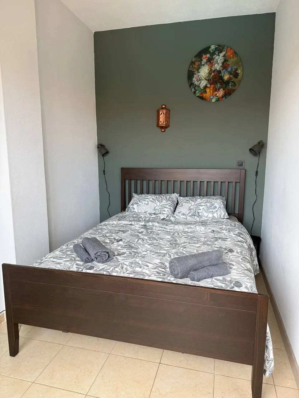 Double bed with patterned bedding, folded towels, and reading lights in the bedroom alcove