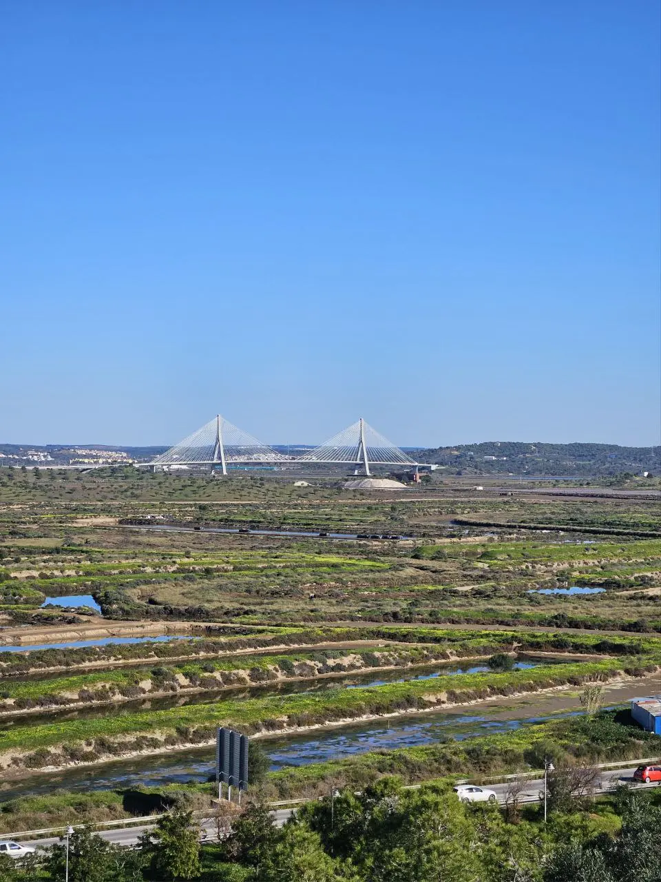 Wide landscape view over salt marshes and a cable-stayed bridge in East Algarve